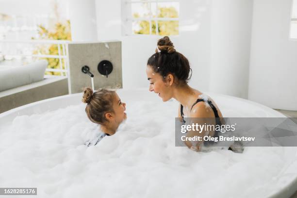 mother and mischief daughter having fun and laughing in huge bath with foam. love and togetherness. - girls in hot tub fotografías e imágenes de stock