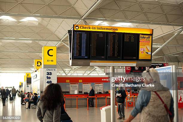 Travellers look at an infomation board in the departures hall at Stansted Airport on February 28, 2013 in Bishop's Stortford, England. The deal...