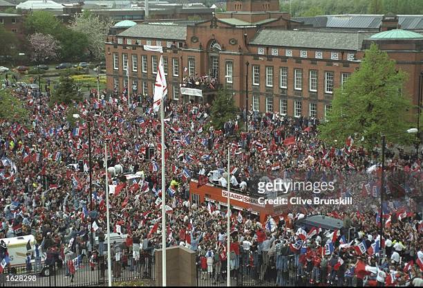 Manchester United supporters salute their team as they drive past in a bus after winning the double of the F A Cup and the Premier League in...