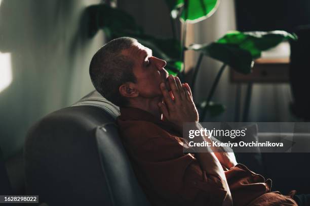 unpleasant pain. sad unhappy handsome man sitting on the sofa and holding his forehead while having headache - suicide stock pictures, royalty-free photos & images