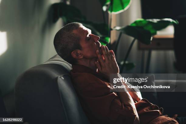 unpleasant pain. sad unhappy handsome man sitting on the sofa and holding his forehead while having headache - suicide imagens e fotografias de stock