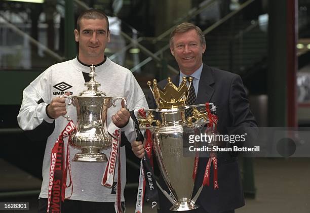 Eric Cantona of Manchester United and Alex Ferguson Manager of Manchester United hold the trophies after winning the F A Cup and the Premier League...