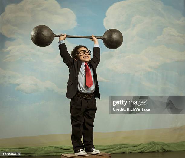 young boy dressed as businessman lifting barbell - strongman stock pictures, royalty-free photos & images