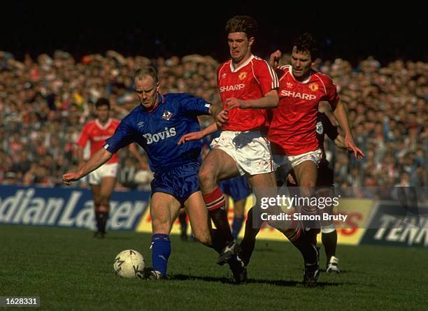 Andy Ritchie of Oldham is tackled by Gary Pallister and Bryan Robson both of Manchester United during the FA Cup Semi-Final at Maine Road in...