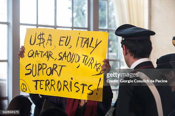 An activist holds a banner up displaying a message of protest after the meeting of the 'Friends of the Syrian People' attended by the U.S. Secretary...