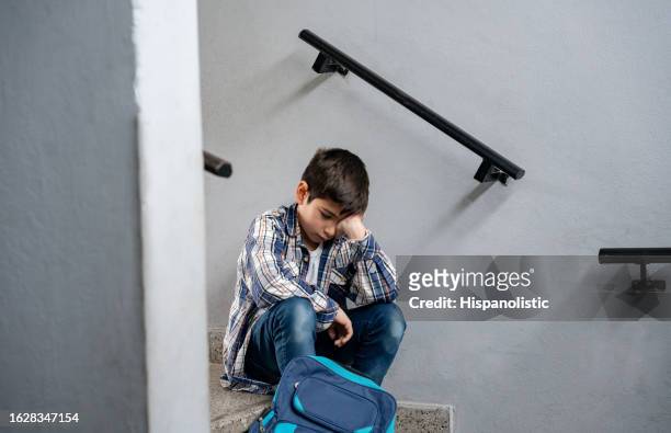 menino triste sentado nas escadas de sua escola parecendo deprimido e solitário - bullying escolar - fotografias e filmes do acervo