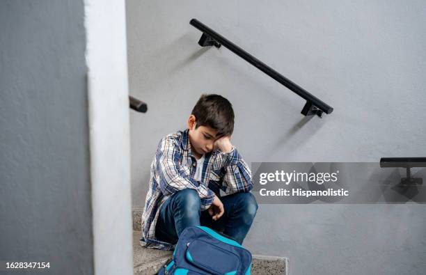 sad little boy sitting at the stairs of his school looking depressed and lonely - mobbning bildbanksfoton och bilder
