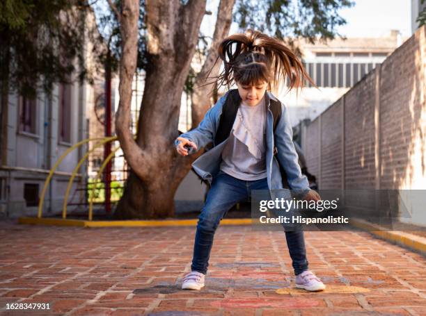 happy caucasian girl jumping at the school playground having a great time - snakes and ladders stock pictures, royalty-free photos & images