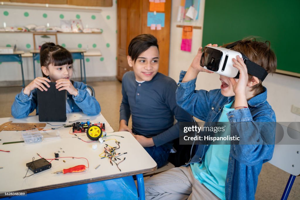 Gruppe von Kindern in der Robotikklasse und eines von ihnen mit Virtual-Reality-Headset, das sehr aufgeregt aussieht