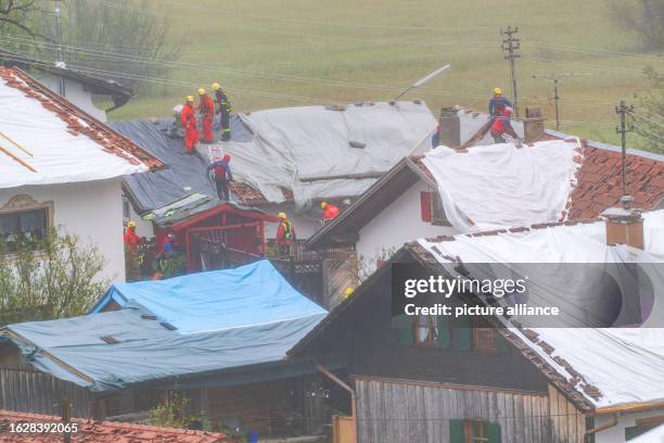 August 2023, Bavaria, Bad Bayersoien: Firefighters secure and cover damaged roofs with large tarpaulins. Thunderstorms plague southern Bavaria over...