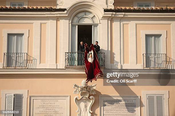 Banner bearing the Papal Seal is unfurled before Pope Benedict XVI waves to pilgrims, for the last time as head of the Catholic Church, from the...