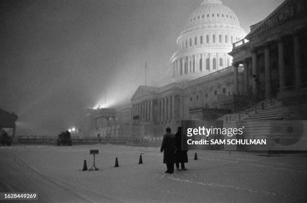 Two policemen stand in front of the Capitol Building on January 20, 1961 in Washington D.C., on the foggy, snowy morning before the inauguration...