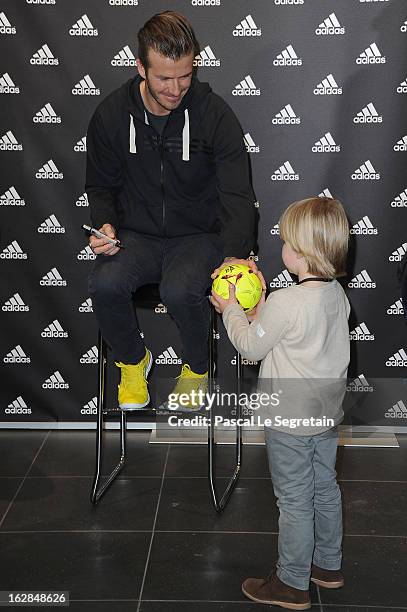 David Beckham meets with a young fan as he attends an autograph session at adidas Performance Store Champs-Elysees on February 28, 2013 in Paris,...