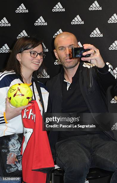 Zinedine Zidane take a photo of himself with a fan as he attends an autograph session at adidas Performance Store Champs-Elysees on February 28, 2013...