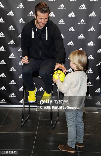 David Beckham meets with a young fan as he attends an autograph session at adidas Performance Store Champs-Elysees on February 28, 2013 in Paris,...