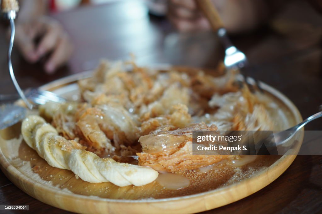 Charcoa Crispy Roti with condensed milk in white plate topping with sugar and sweetened condensed milk, dessert snack sweet food