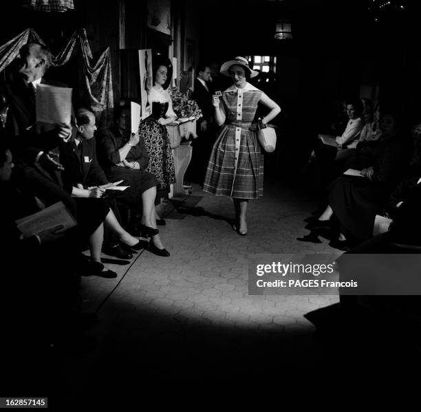 High Fashion. Dans le show-room d'une maison de haute couture, un mannequin, présentant, devant des visiteurs assis de part et d'autre d'un tapis de...