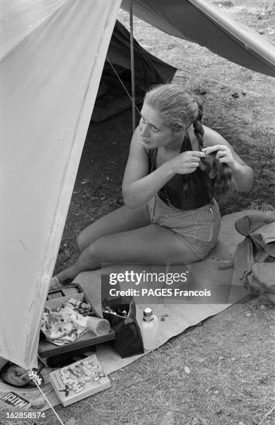 Camping On The French Rivieira, August 1955. La Côte d'Azur en 1955. Touristes au camping. Femme assise par terre, se tressant les cheveux.