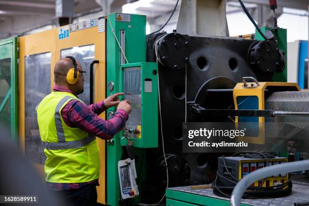 male apprentice engineer working with cnc machine in factory - industriearbeider stockfoto's en -beelden