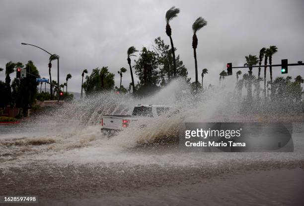 Vehicles drives through a flooded street from Tropical Storm Hilary on August 20, 2023 in Cathedral City, California. More than 40 million people are...