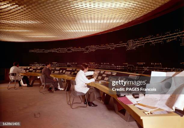 The Grand Metro Of Grand Paris. En 1969, dans une salle de contrôle de la circulation de la RATP, trois employés assis derrière un tableau de bord,...