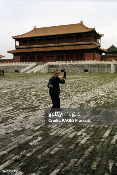 China. En Chine, à Pekin, sur une place devant un temple de la Cité interdite, un homme avec une veste col mao et des lunettes, pratiquant un art...