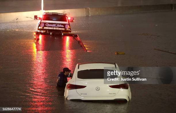 Tow truck driver attempts to pull a stranded car out of floodwaters on the Golden State Freeway as tropical storm Hilary moves through the area on...