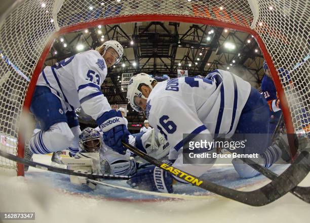 Goaltender James Reimer and defensemen Mike Kostka and Carl Gunnarsson of the Toronto Maple Leafs manage to stop Kyle Okposo of the New York...