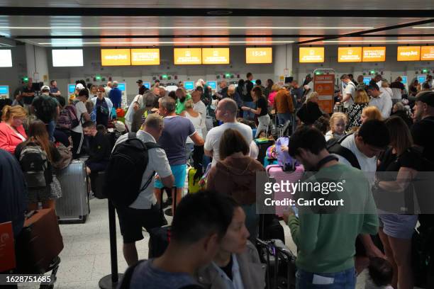 People wait near the EasyJet check-in desks at Gatwick Airport on August 28, 2023 in Crawley, United Kingdom. The United Kingdom's air traffic...