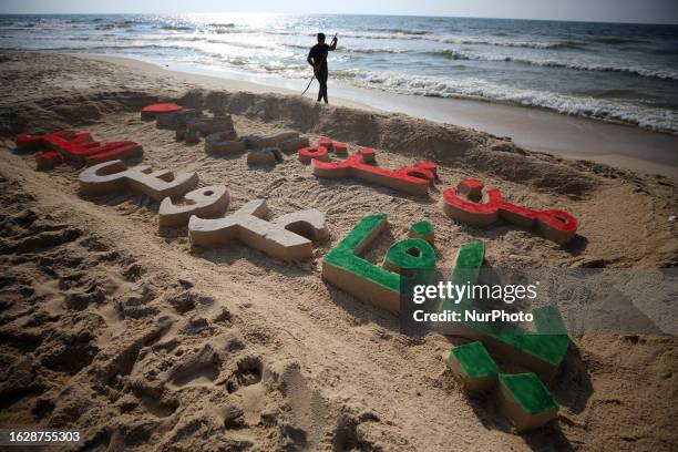 Palestinians writing by sea sand a slogan say ''From Gaza to Jaffa, Jaffa is the sea bride'' on a beach in Gaza City, on August 28, 2023.