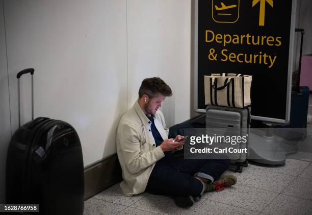 Man checks his phone as he waits at Gatwick Airport on August 28, 2023 in Crawley, United Kingdom. The United Kingdom's air traffic control systems...