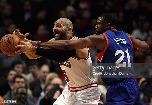 Thaddeus Young of the Phildelphia 76ers tries to knock the ball away from Carlos Boozer of the Chicago Bulls at the United Center on February 28,...