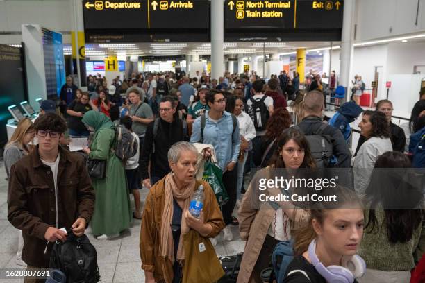 People wait near check-in desks at Gatwick Airport on August 28, 2023 in Crawley, United Kingdom. The United Kingdom's air traffic control systems...