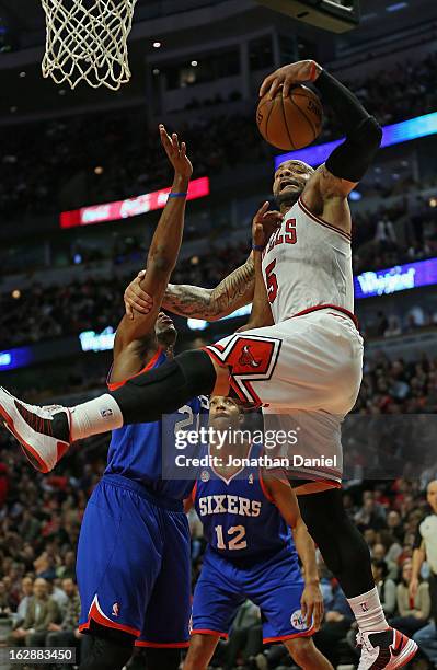 Carlos Boozer of the Chicago Bulls rebounds over Thaddeus Young of the Phildelphia 76ers at the United Center on February 28, 2013 in Chicago,...