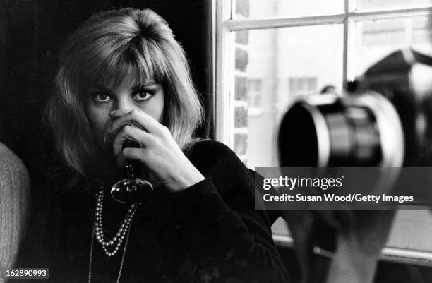 Italian actress Monica Vitti drinks from a wine glass during the filming of 'Modesty Blaise' , 1965.