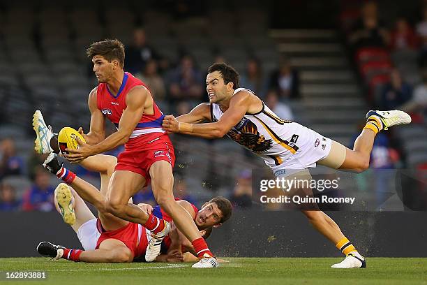 Koby Stevens of the Bulldogs handballs whilst being tackled by Jordan Lewis of the Hawks during the round two NAB Cup AFL match between the Western...
