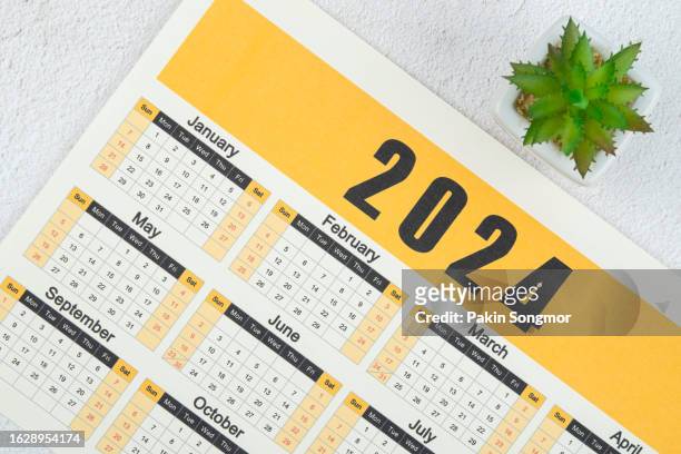 top views of the calendar desk 2024 is the month for the organizer to plan and deadline with houseplant against a wooden table background. - calender imagens e fotografias de stock