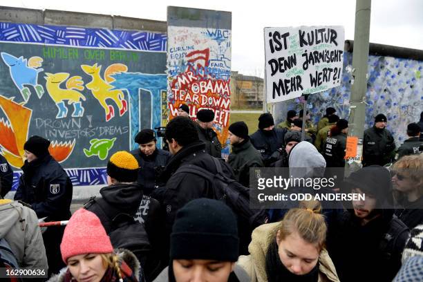 Police face protesters with a banner reading 'Does culture still means anything?' during the removal of a section of the East Side Gallery, a 1,3 km...