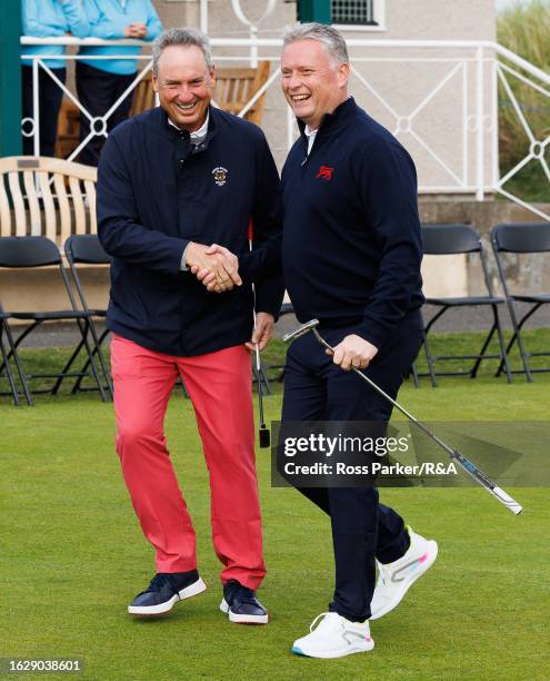 Team USA captain Mike McCoy shakes hands with Team Great Britain and Ireland captain Stuart Wilson during a putting contest at the Himalayas putting...