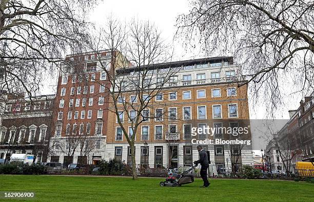 Gardener mows the lawn in St James's Square against a backdrop of BP Plc's headquarters in London, U.K., on Thursday, Feb. 28, 2013. BP Plc's push to...