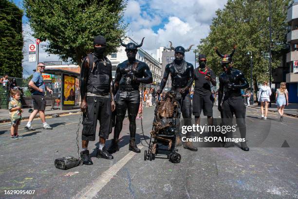 Black-painted men pose for a photo. It used to be black oil but they replaced it with black paint to cover the body. The Notting Hill Carnival is one...