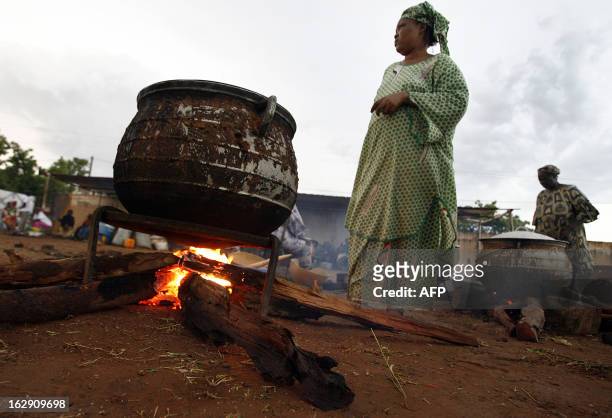 Women cook 05 June 2007 near the "Babemba Traore" stadium in Sikasso, Mali, after a strong storm destroyed tents used to gather food during a forum...