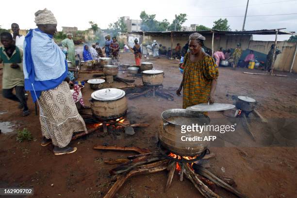 Women cook 05 June 2007 near the "Babemba Traore" stadium in Sikasso, Mali, after a strong storm destroyed tents used to gather food during a forum...