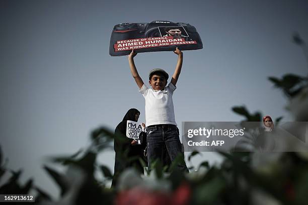 Bahraini boy holds a placard in the shape of a camera bearing a picture of jailed freelance photographer Ahmed Humaidan during an anti-government...