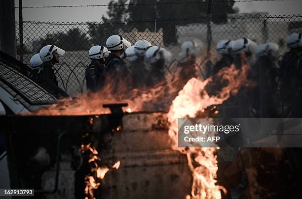 Bahraini riot policemen stand next to burning trash containers that were set on fire by protesters to block a road as police reopen the road...