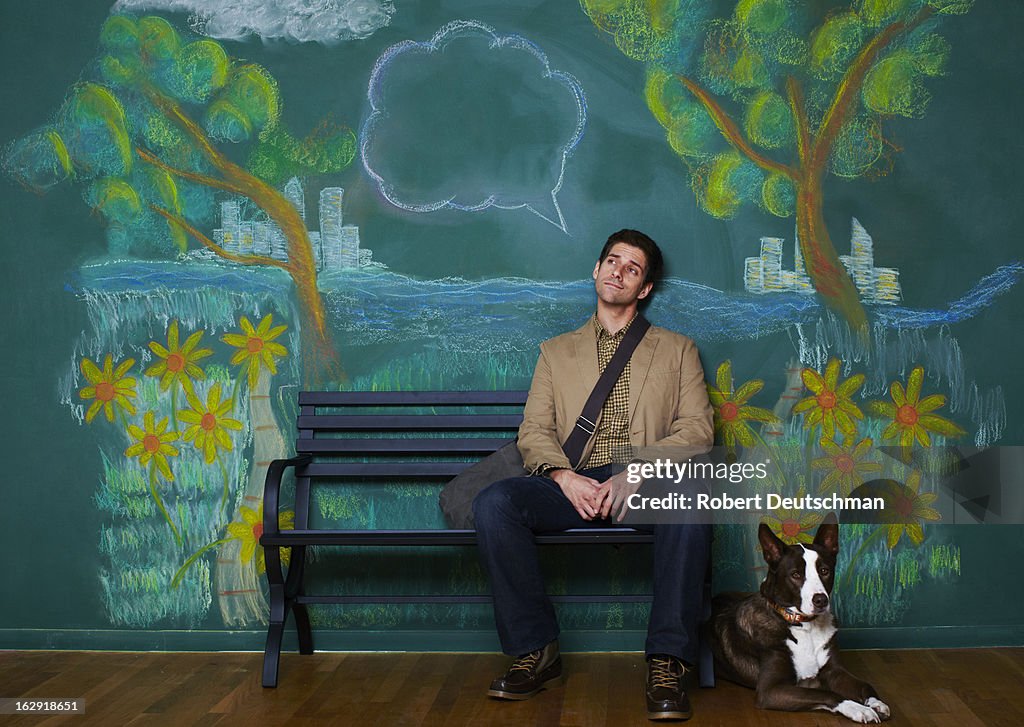 A man and dog sitting on a park bench thinking.