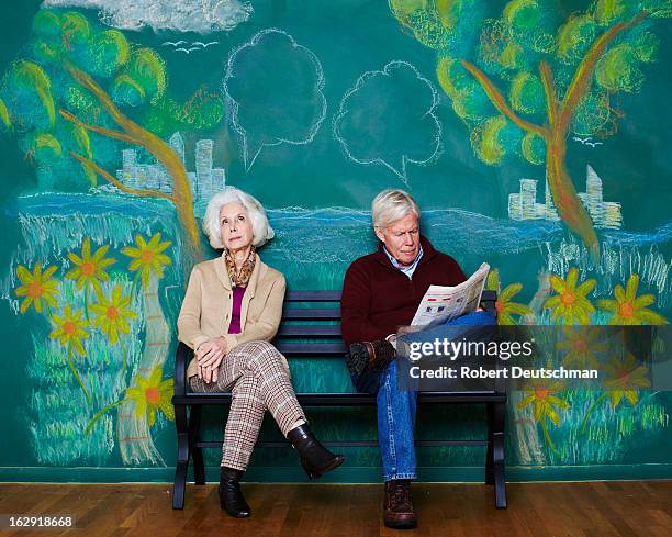 an old man and woman sitting on a park bench. - studio city photos et images de collection