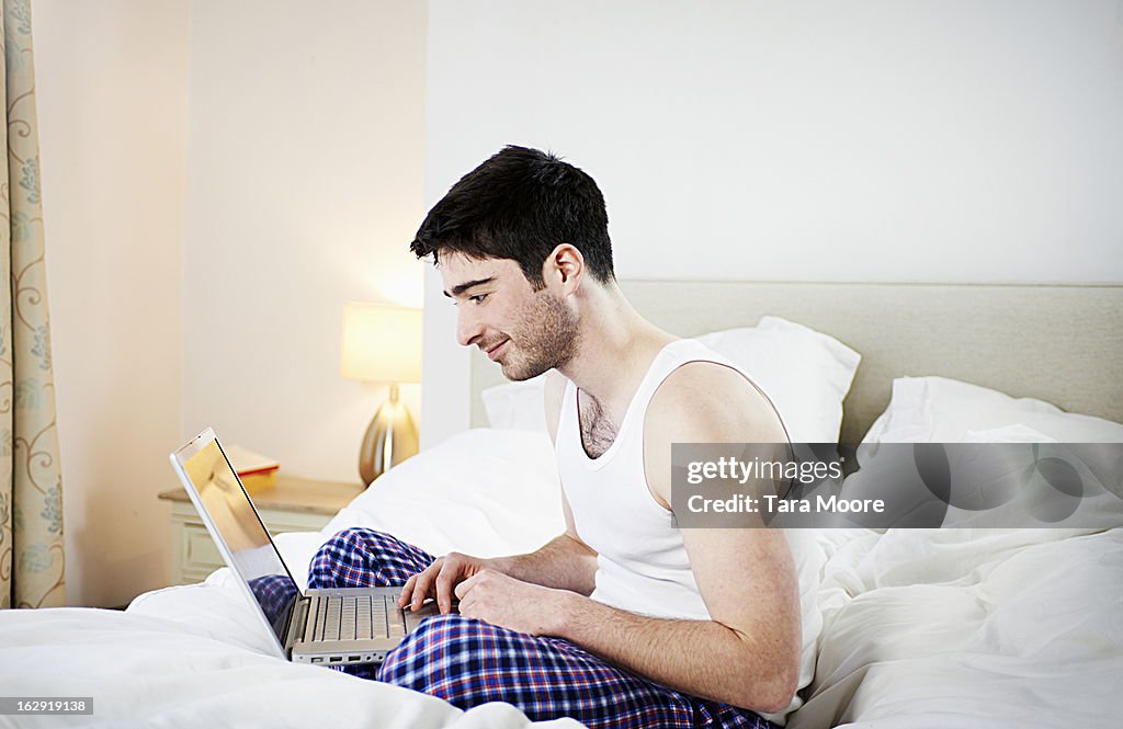 Man sitting in bed looking at computer