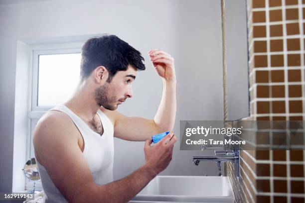 man applying gel to hair in bathroom - vest stock pictures, royalty-free photos & images