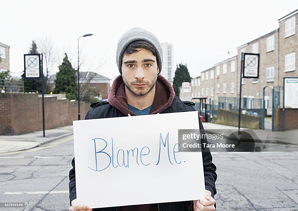Young man holding sign in urban street